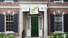 The front door of a final club, where a hand-made sign saying "The lizard" with a cartoon lizard has been hung above the door