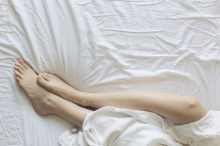 A woman's legs on a clean white bed 